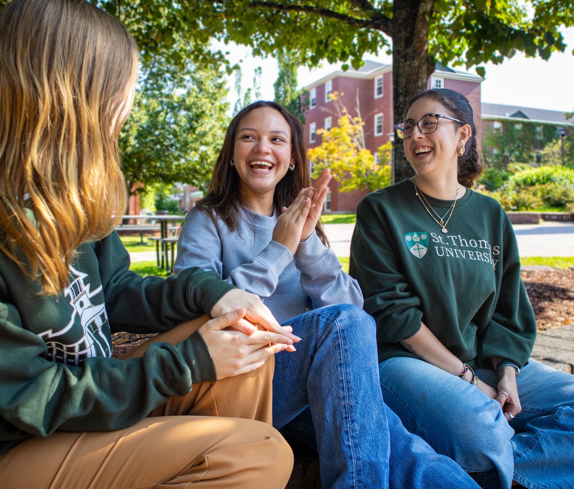 A photo of three female students sitting, one laughing